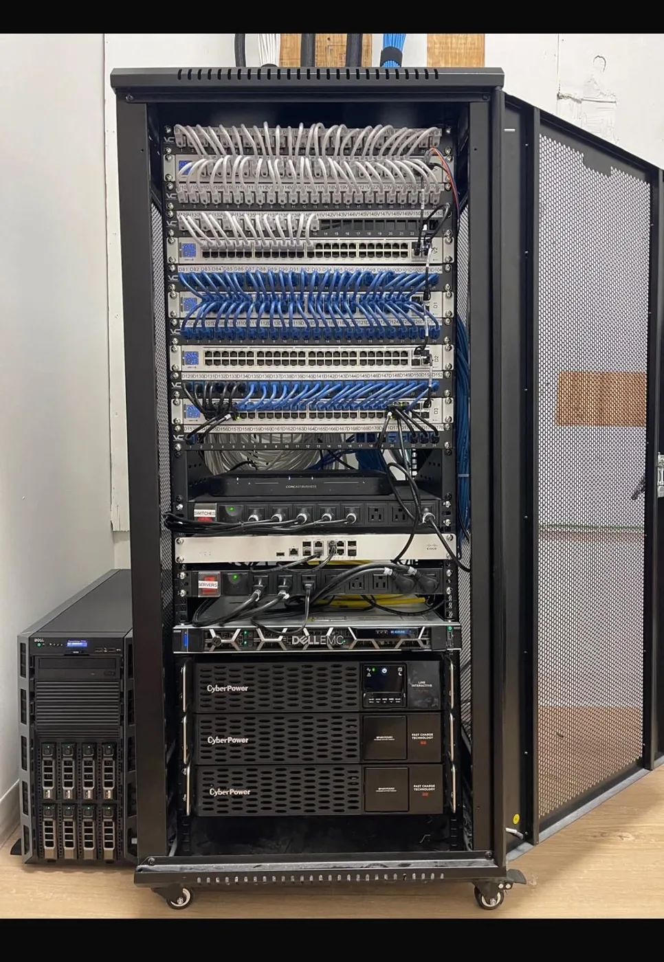 A commercial equipment rack installed by KeenAI with labelled patch panels, network switching, a server and rack-mounted UPS units