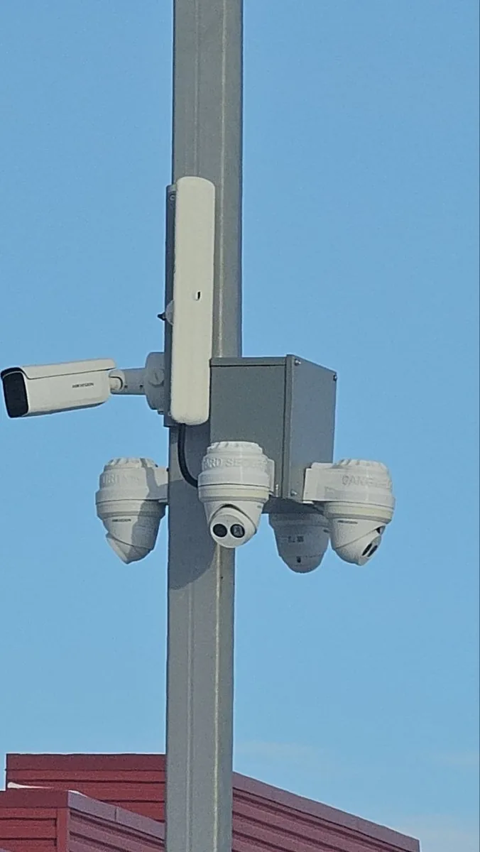 A pole-mounted cluster of bullet and dome cameras with a wireless bridge, installed by KeenAI to cover a site