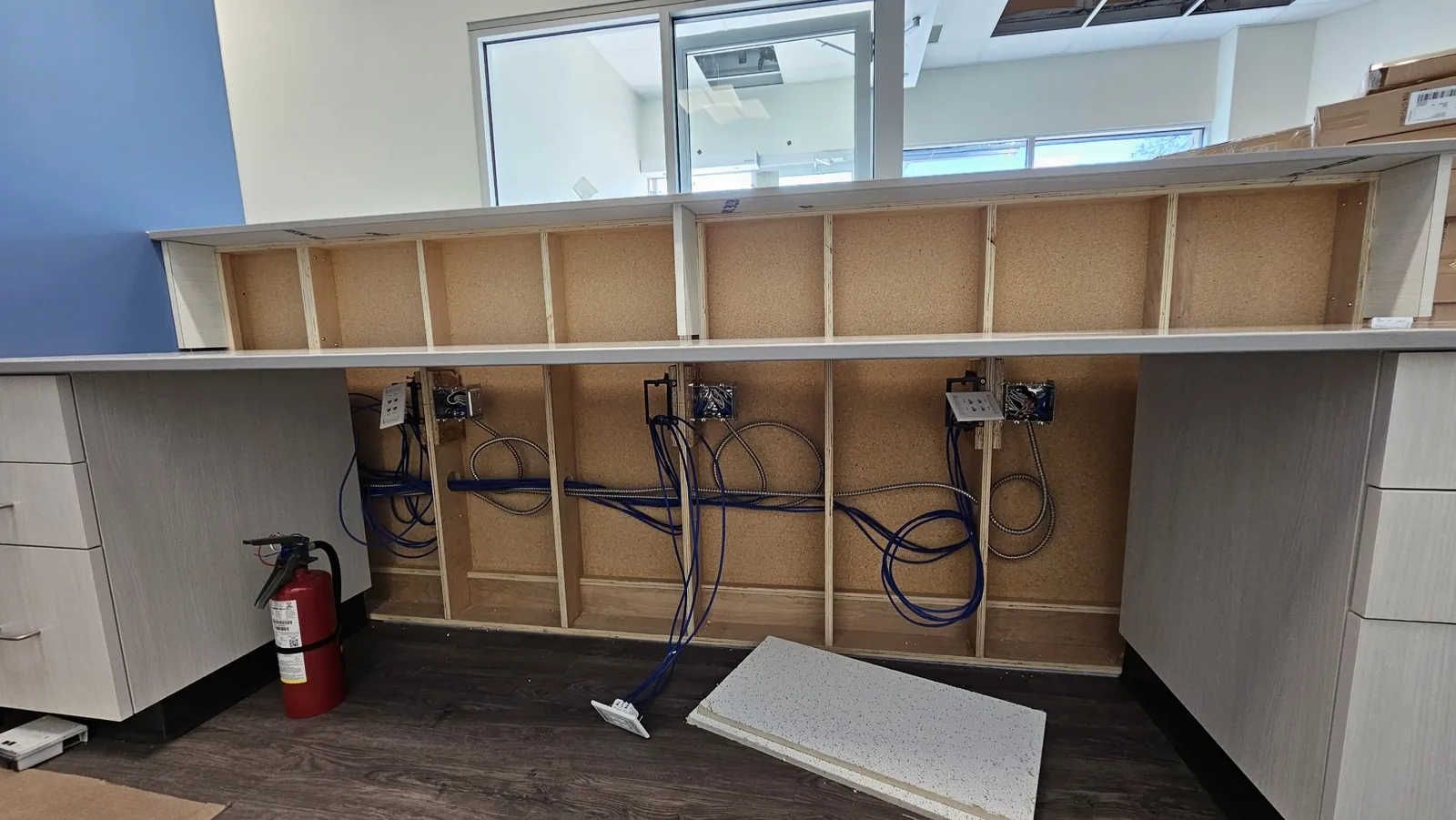 Data and armoured conduit runs into open millwork at rough-in stage, installed by KeenAI before the finishes went on